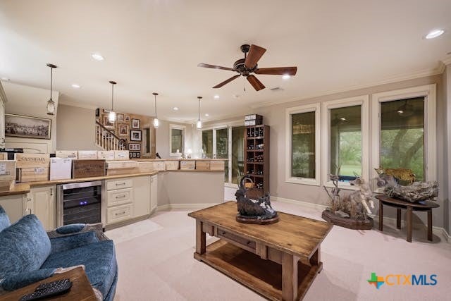 carpeted living room featuring ornamental molding, ceiling fan, and wine cooler