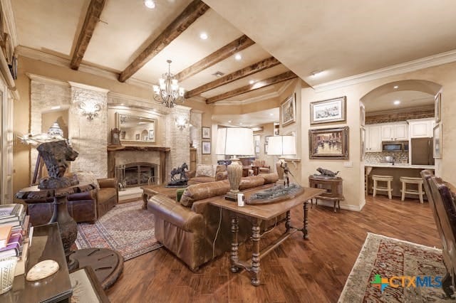 living room with ornamental molding, beamed ceiling, an inviting chandelier, and dark hardwood / wood-style floors