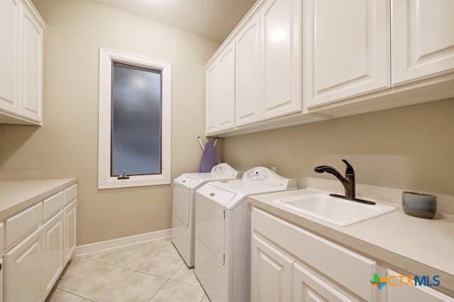 laundry room featuring washing machine and dryer, cabinets, sink, and light tile patterned flooring