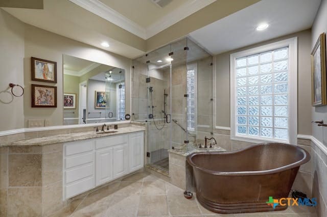 bathroom featuring independent shower and bath, vanity, ornamental molding, and plenty of natural light