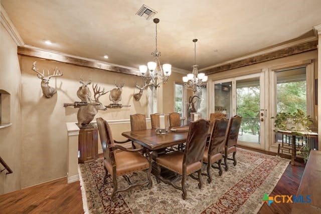 dining room featuring hardwood / wood-style flooring, ornamental molding, and a notable chandelier