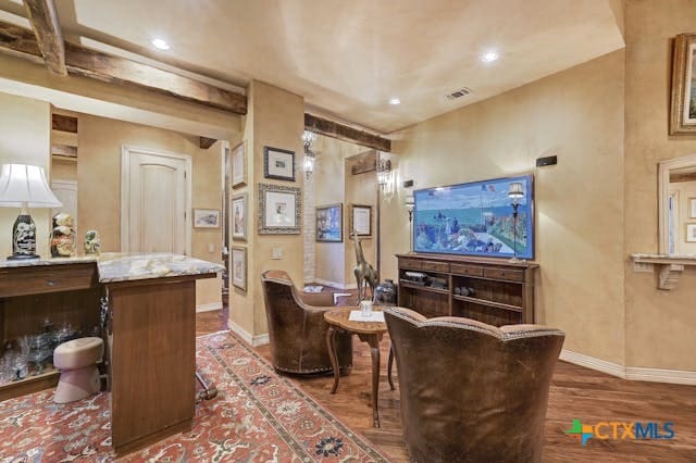 living area with dark wood-type flooring and beam ceiling