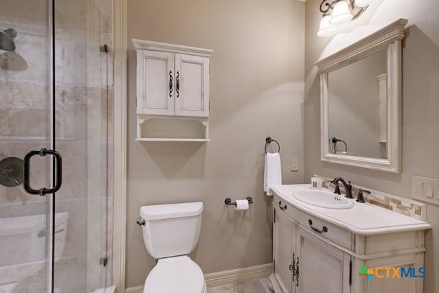 bathroom with walk in shower, vanity, and toilet