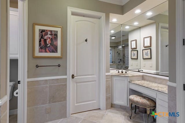 bathroom with toilet, vanity, tile patterned floors, and a shower