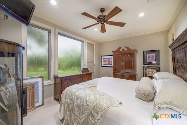 carpeted bedroom with ceiling fan and crown molding