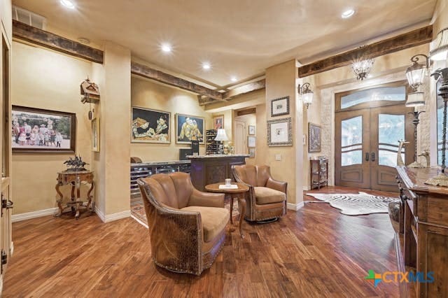 living area featuring french doors, hardwood / wood-style floors, and beam ceiling