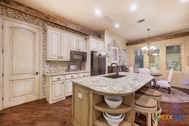 kitchen featuring stainless steel appliances, dark wood-type flooring, a center island with sink, hanging light fixtures, and sink