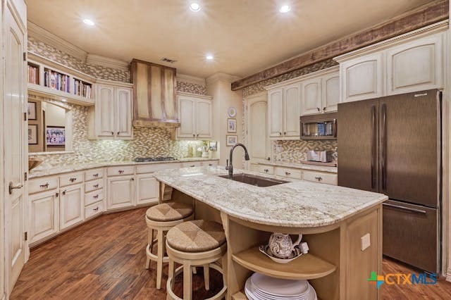 kitchen featuring dark hardwood / wood-style flooring, a center island with sink, sink, crown molding, and fridge