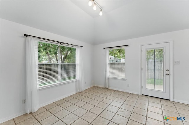 unfurnished room with vaulted ceiling and light tile patterned floors