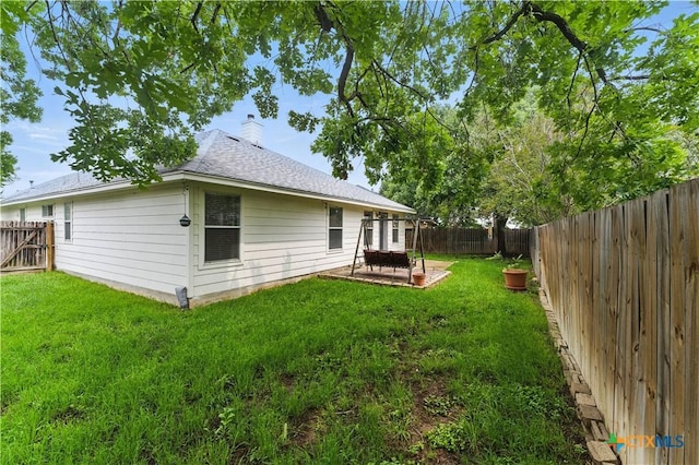 back of house featuring roof with shingles, a chimney, and a patio