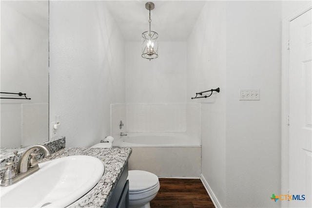 full bathroom with toilet, wood finished floors, vanity, and a tub to relax in
