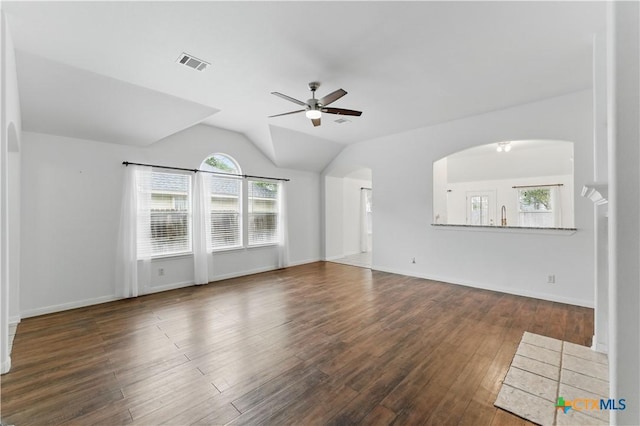 unfurnished living room featuring a ceiling fan, healthy amount of natural light, arched walkways, wood finished floors, and vaulted ceiling