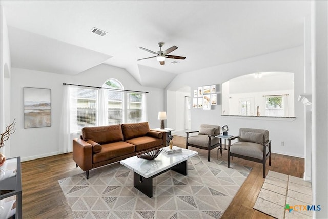 living room featuring light wood-style floors, a ceiling fan, plenty of natural light, and vaulted ceiling