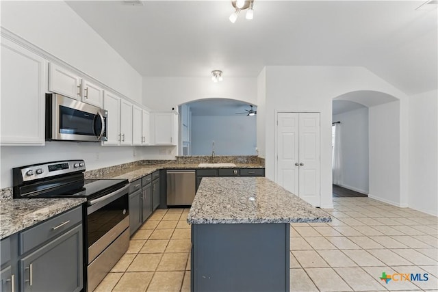 kitchen with appliances with stainless steel finishes, arched walkways, a kitchen island, ceiling fan, and white cabinetry
