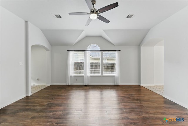 empty room with arched walkways, a ceiling fan, wood finished floors, vaulted ceiling, and baseboards