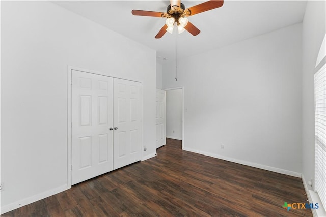 unfurnished bedroom featuring dark wood-style flooring, baseboards, a closet, and ceiling fan
