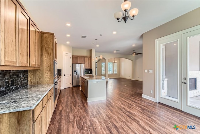 462 Stagecoach Trl, San Marcos, TX 78666 - kitchen featuring appliances with stainless steel finishes, arched walkways, tasteful backsplash, dark wood-style floors, and recessed lighting