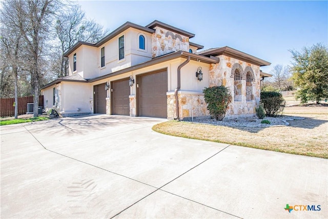 view of front of home with fence, stucco siding, concrete driveway, a garage, and stone siding