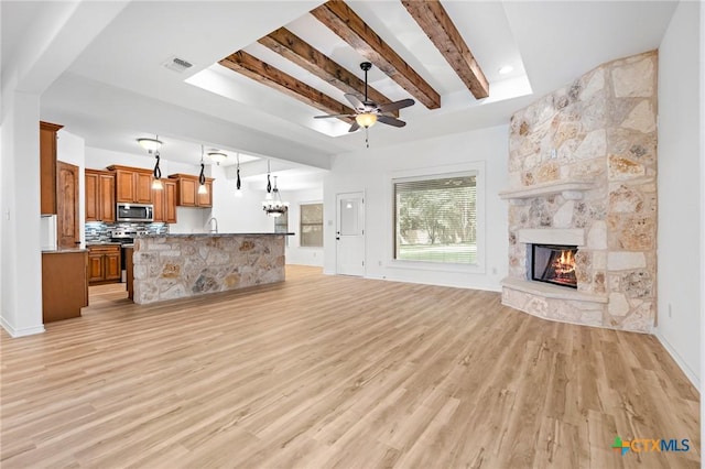 1010 Woodland Bend Cir, Salado, TX 76571 - unfurnished living room with light wood finished floors, a ceiling fan, a fireplace, and beam ceiling