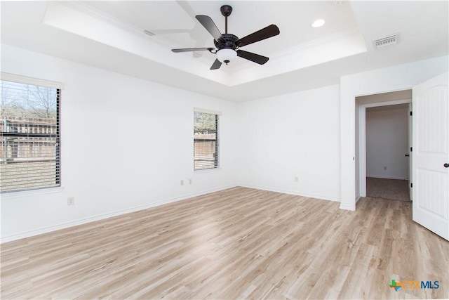 spare room featuring a tray ceiling, plenty of natural light, and visible vents