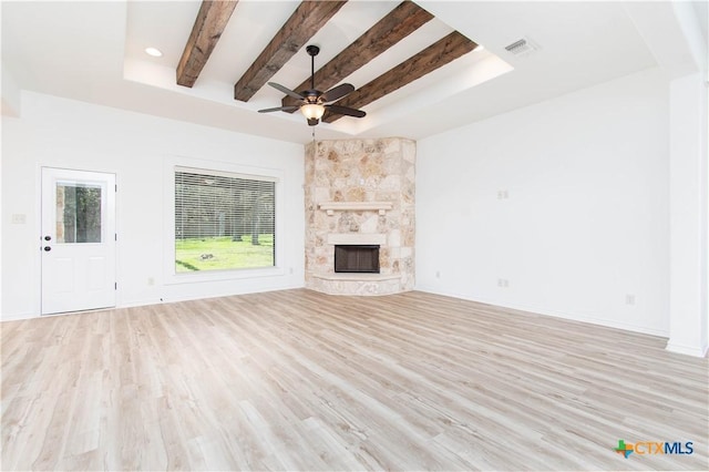 unfurnished living room featuring beamed ceiling, a fireplace, light wood-type flooring, and baseboards