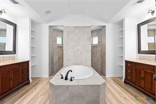 1010 Woodland Bend Cir, Salado, TX 76571 - bathroom featuring a garden tub, wood finished floors, walk in shower, two vanities, and vaulted ceiling
