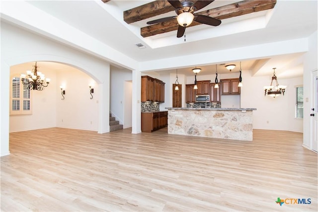 unfurnished living room with ceiling fan with notable chandelier, beamed ceiling, visible vents, and light wood-type flooring