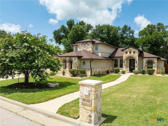 1010 Woodland Bend Cir, Salado, TX 76571 - mediterranean / spanish house featuring stone siding, a front yard, stucco siding, and roof with shingles