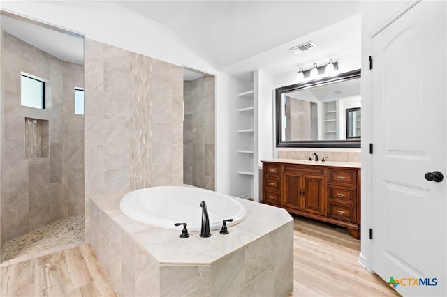 1010 Woodland Bend Cir, Salado, TX 76571 - full bathroom featuring a garden tub, vanity, vaulted ceiling, built in shelves, and wood finished floors
