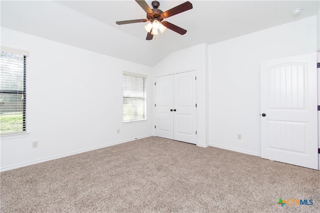 unfurnished bedroom with vaulted ceiling, carpet flooring, a ceiling fan, and baseboards