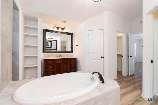 bathroom featuring a bath, visible vents, vanity, and wood finished floors