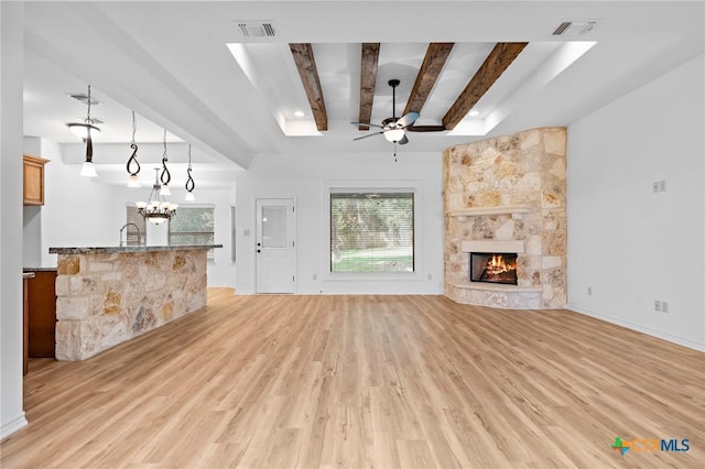 1010 Woodland Bend Cir, Salado, TX 76571 - unfurnished living room with light wood-type flooring, ceiling fan, a fireplace, a tray ceiling, and beam ceiling