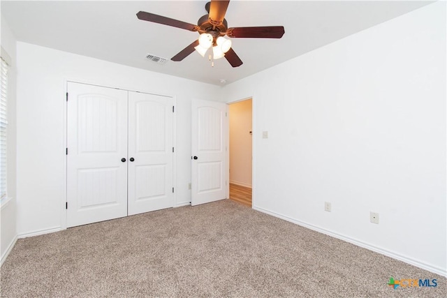 unfurnished bedroom featuring visible vents, a ceiling fan, a closet, baseboards, and light colored carpet