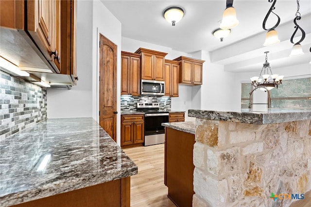 1010 Woodland Bend Cir, Salado, TX 76571 - kitchen featuring appliances with stainless steel finishes, brown cabinetry, tasteful backsplash, light wood-type flooring, and decorative light fixtures