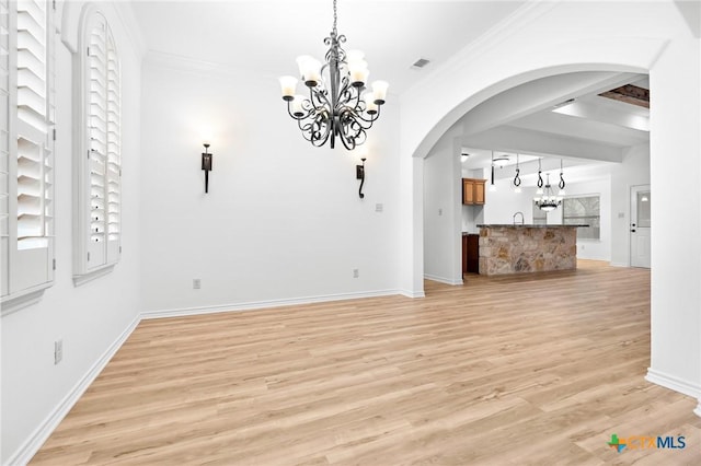 1010 Woodland Bend Cir, Salado, TX 76571 - unfurnished living room featuring a chandelier, arched walkways, light wood-style floors, and crown molding