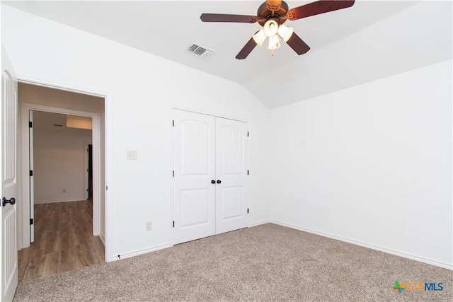 unfurnished bedroom featuring visible vents, carpet floors, a closet, and vaulted ceiling