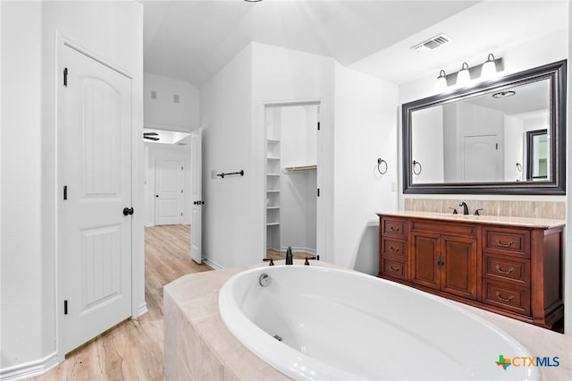 1010 Woodland Bend Cir, Salado, TX 76571 - full bath featuring a relaxing tiled tub, vanity, a closet, wood finished floors, and lofted ceiling