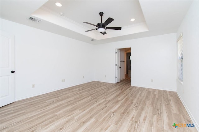 spare room with recessed lighting, a tray ceiling, visible vents, and light wood finished floors