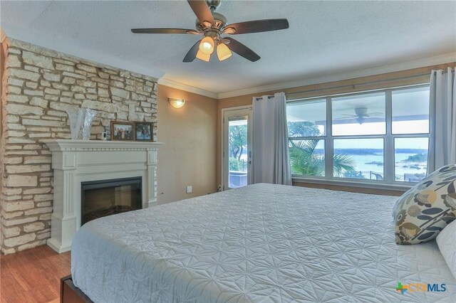 522 Woodland Point Rd, Belton, TX 76513 - bedroom featuring crown molding, a textured ceiling, a glass covered fireplace, and wood finished floors