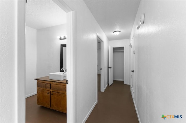 corridor with sink and a textured ceiling