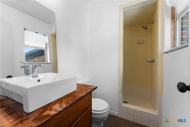 bathroom with a tile shower, sink, and toilet