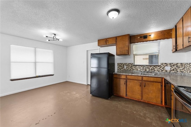 kitchen featuring sink, decorative backsplash, plenty of natural light, and black fridge