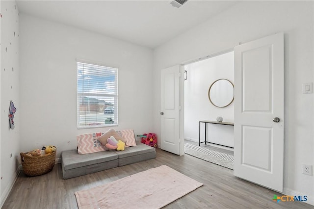 living area with wood finished floors, visible vents, and baseboards