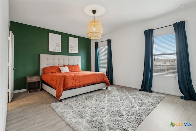 bedroom with an accent wall, baseboards, and wood finished floors