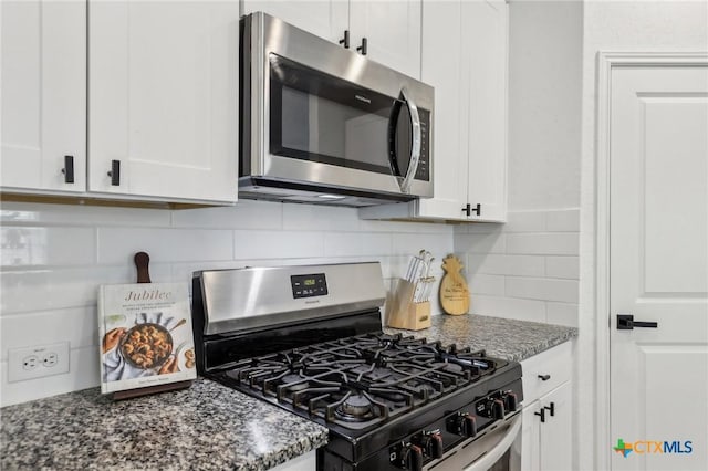 kitchen with white cabinetry, appliances with stainless steel finishes, decorative backsplash, and dark stone countertops