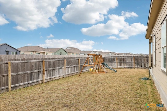 view of yard featuring a playground, a fenced backyard, and a residential view