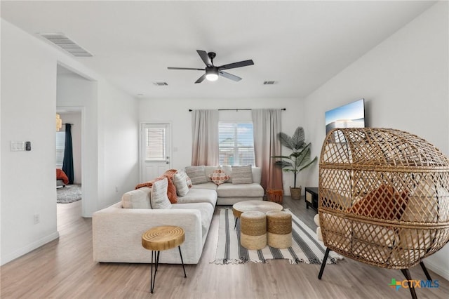 living room featuring a ceiling fan, visible vents, and wood finished floors