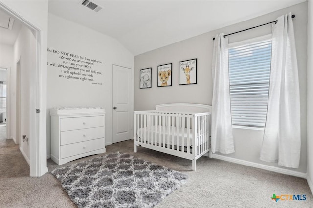 bedroom with carpet floors, lofted ceiling, visible vents, a crib, and baseboards