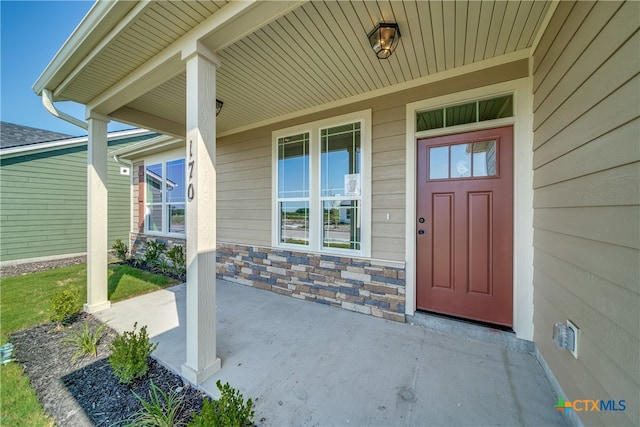 property entrance with stone siding and a porch