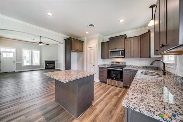 kitchen featuring stainless steel appliances, hardwood / wood-style flooring, sink, ornamental molding, and a kitchen island